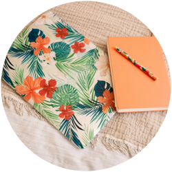 A notebook with a tropical print and a pen on a bed.
