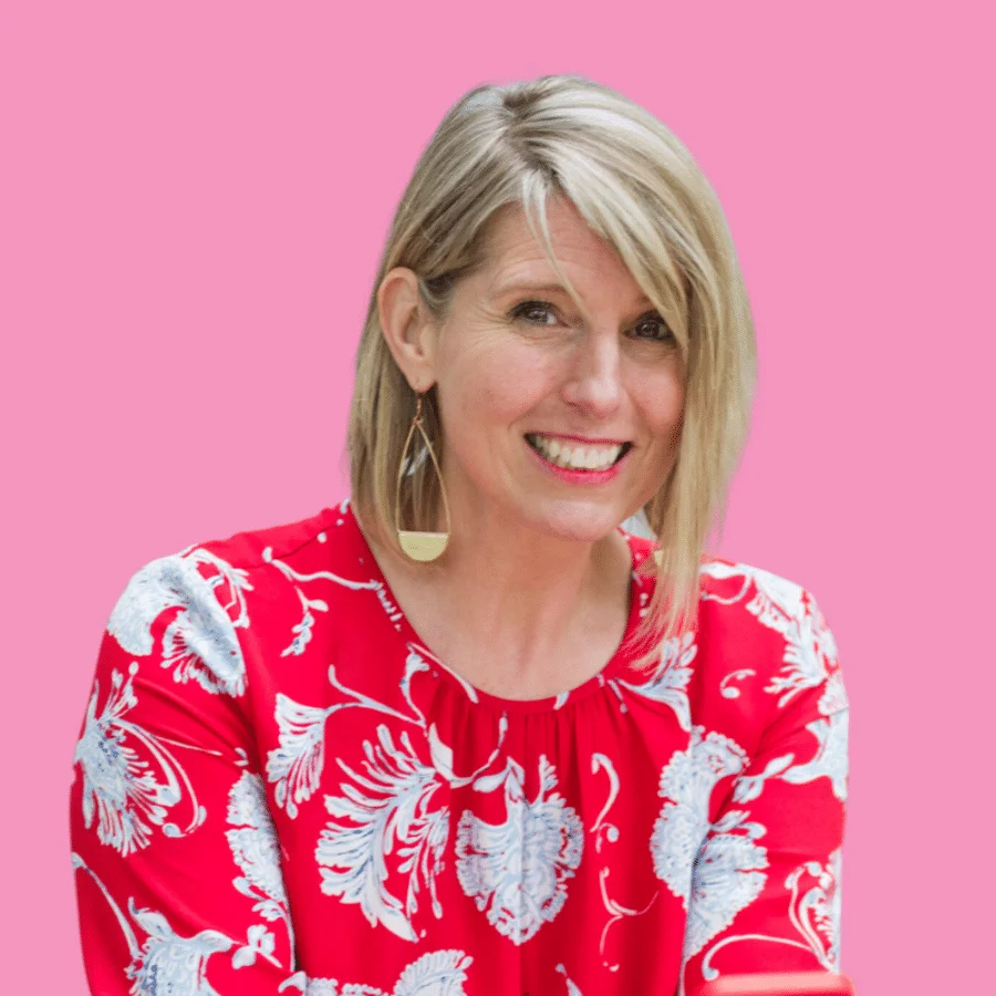 A woman smiling in front of a pink background.