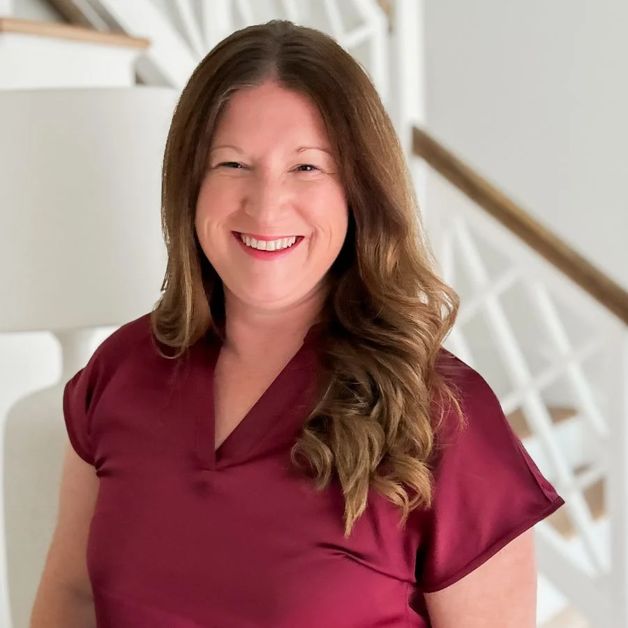 Jocelyn Wykoff in a maroon top smiling in front of a staircase.