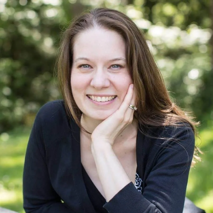 Brenda Cadman smiling at the camera with her head resting on her hand, outdoors.